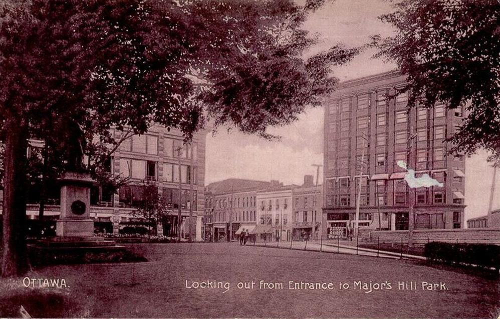 Postcard showing the southeast corner of Major's Hill Park, facing the Daly Building and the intersection of Rideau Street and Mackenzie Avenue.  In…